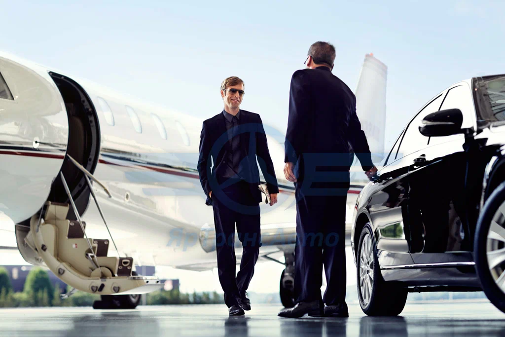 SUV at Hamilton Airport arrivals with chauffeur holding client's name sign